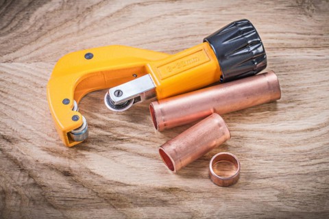 Horizontal image of brass water pipe cutter on wooden board plumbing concept