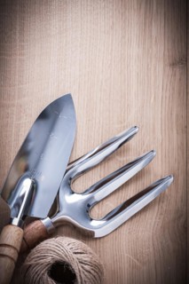 Stainless hand spade trowel fork and hank of string on vintage wooden board gardening concept