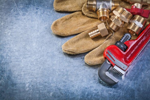 Adjustable wrench protective gloves brass pipe connectors on metallic background plumbing concept