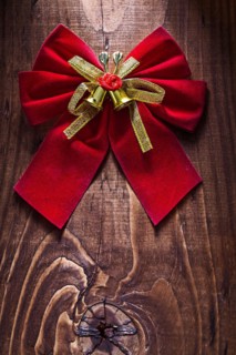 Beautiful red Christmas bow with gold ribbon and bells on an old wooden board