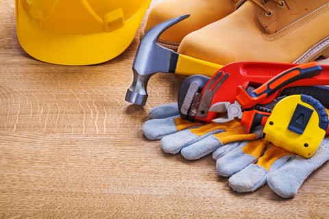 Horizontal view helmet boots glove tapeline monkey spanner hammer pliers on wooden board