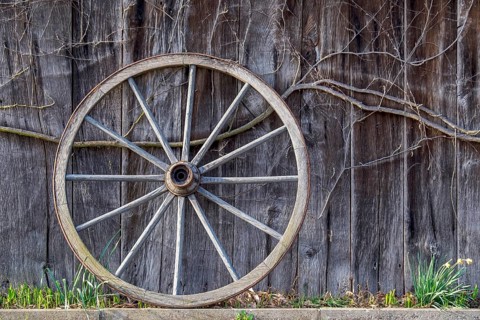 Old wagon wheel leaning against a barn wall