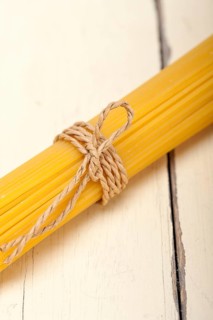 Italian pasta spaghetti tied with a rope on a rustic table