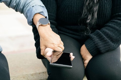Two Spanish-Latino women with smartphones and smartwatches