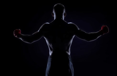 Kickboxer in red bandages raised his hands in victory. Back view. The concept of mixed martial arts. MMA