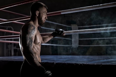 Kickboxer holding on to the ring rope. Sports competitions. Fight night. The concept of mixed martial arts. MMA