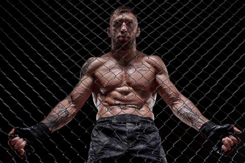 Portrait of a powerful fighter behind the steel bars of the octagon. The concept of sports