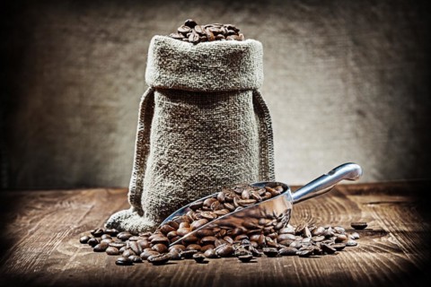Scoop and sack with coffee beans on vintage wood table