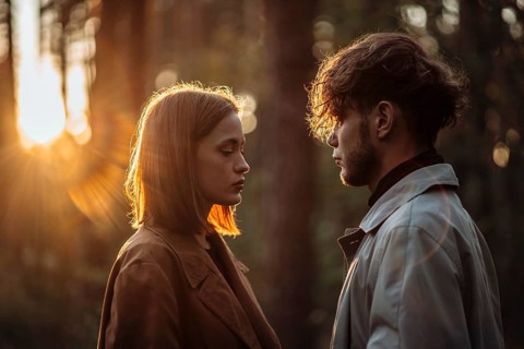 Beautiful fashionable couple in love in the forest at sunset in autumn