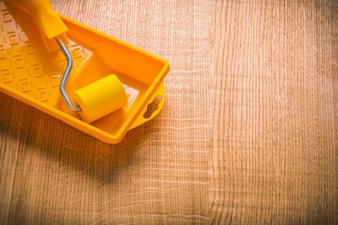 Copyspace picture yellow paint roller in tin on wooden board