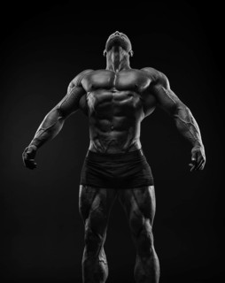 Silhouette of a strong bodybuilder. Confident young fitness athlete with a powerful body and perfect abs. Black and white photography. Dramatic light. Mixed media