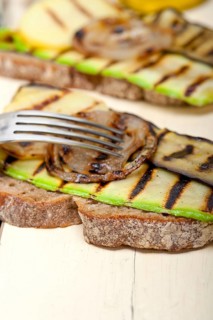 Grilled vegetables on rustic bread over wood table