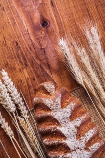 Bread and ears of wheat on a vintage wooden board Food and drink concept