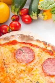 Italian original thin crust pepperoni pizza with fresh vegetables on background