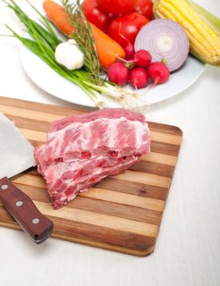 Chopping fresh pork ribs with vegetables and herbs ready to cook