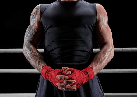 Red bandages on the hands of a kickboxer against the background of the ropes of the ring. The concept of mixed martial arts. MMA