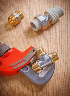 Close-up of pipe fasteners and spanner on wooden board