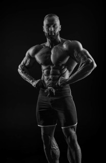 Silhouette of a strong bodybuilder. Confident young fitness athlete with a powerful body and perfect abs. Black and white photography. Dramatic light. Mixed media