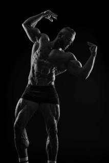 Silhouette of a strong bodybuilder. Confident young fitness athlete with a powerful body and perfect abs. Black and white photography. Dramatic light. Mixed media