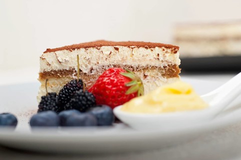 Classic Italian tiramisu dessert with berries and custartd pastry cream on side