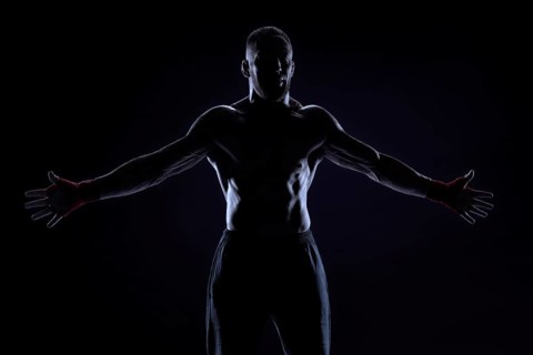 Kickboxer in red bandages poses on a blue background with his arms apart. The concept of mixed martial arts. MMA