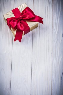 Gift box in glittery paper with bow on wooden board holidays concept