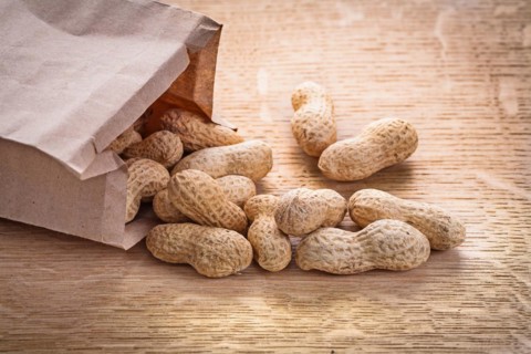 Horizontal vercion peanuts poured from paper bag on wooden board food and drink still life