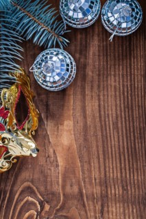 Christmas background mirror disco balls and carnival mask branch of fir tree on old wooden board with copyspace