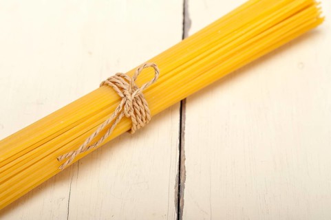 Italian pasta spaghetti tied with a rope on a rustic table