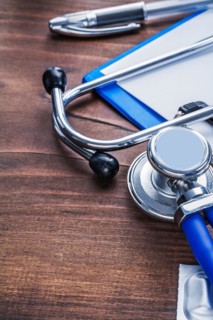 Stethoscope clipboard biros on vintage wooden board wery close-up view medical comcept