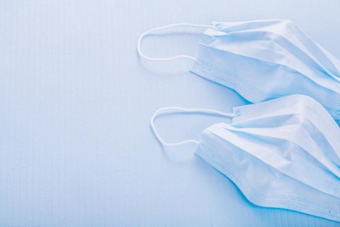 Two disposable face masks on a blue background with spaces
