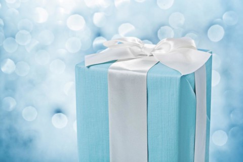 Close up view blue gift box with white bow on blurred background