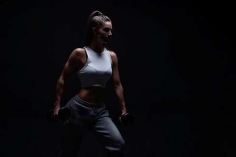 Athletic fitness woman posing in the studio on a dark background. Photo of an attractive woman in fashionable sportswear. Sports and healthy lifestyle. Mixed media