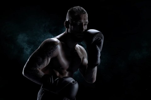 Kickboxer in black gloves posing on a background of smoke. The concept of mixed martial arts. MMA