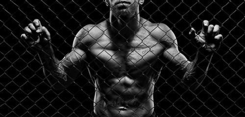 Black and white image of a man in a boxing cage. The concept of sports