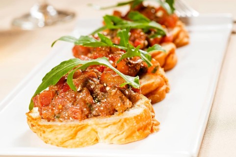 Fresh tipycal italian bruschetta with tomato and arugula on top