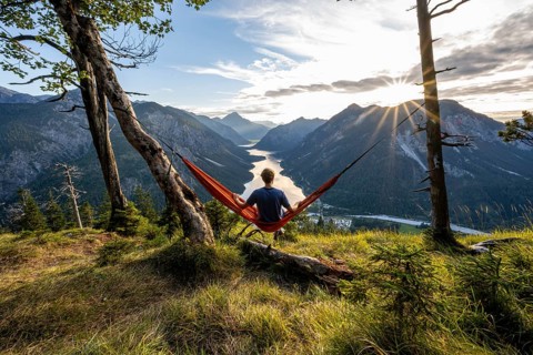 Young man sitting in an orange hammock