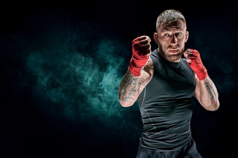 Kickboxer in red bandages is boxing against a background of smoke. The concept of mixed martial arts. MMA