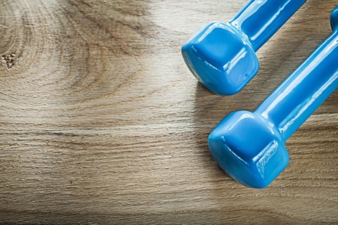 Blue dumbbell weights on wooden board fitness concept