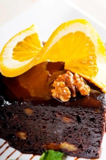 Fresh baked delicious chocolate and walnuts cake with slice of orance on top