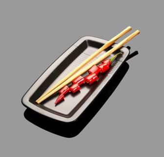 Fresh red chili peppers on a plate with chopstikcs over grey reflective surface
