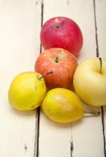 Fresh fruits apples and pears on a white wood table