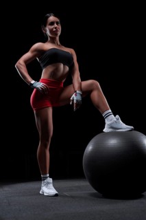 Athletic girl working out in gym. Fitness woman training with pilates ball. Mixed media