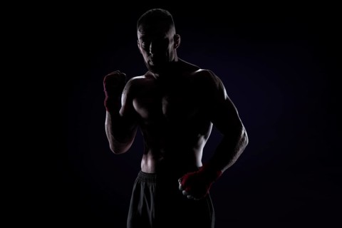 Kickboxer in red bandages posing on a blue background. The concept of mixed martial arts. MMA