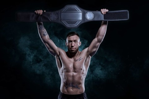Kickboxer victoriously raises the belt won in the tournament against the backdrop of smoke. Sports competitions. Fight night. The concept of mixed martial arts. MMA