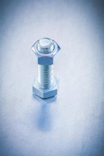 Threaded screw bolt with construction nut on metallic background repairing concept