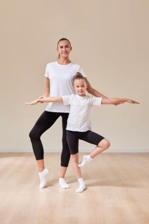 Beautiful woman teacher and a little girl perform dance movements in a bright studio. The concept of education