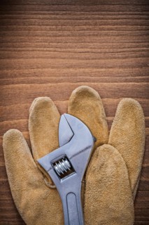 Adjustable key leather protective gloves on wood board construction concept