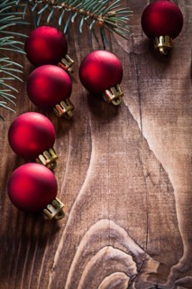Group of red Christmas baubles and fir branch on an old wooden board