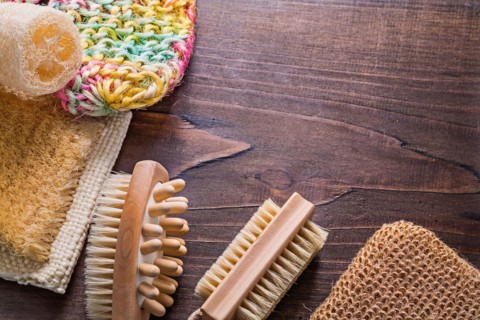 Bath sticks loofah massagers on vintage wooden board with copy area